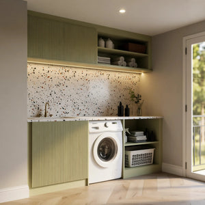 Balham fitted laundry room in London seen from the doorway: the sage fluted sink base, washer bay and open shelves under the terrazzo worktop, with the lit upper cupboard and shelves above. Made to measure by Metro Home Interiors