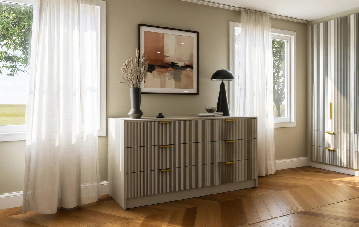 Bloomsbury fluted chest of drawers: a wide six-drawer chest in greige with fluted fronts and brass bar handles between two windows