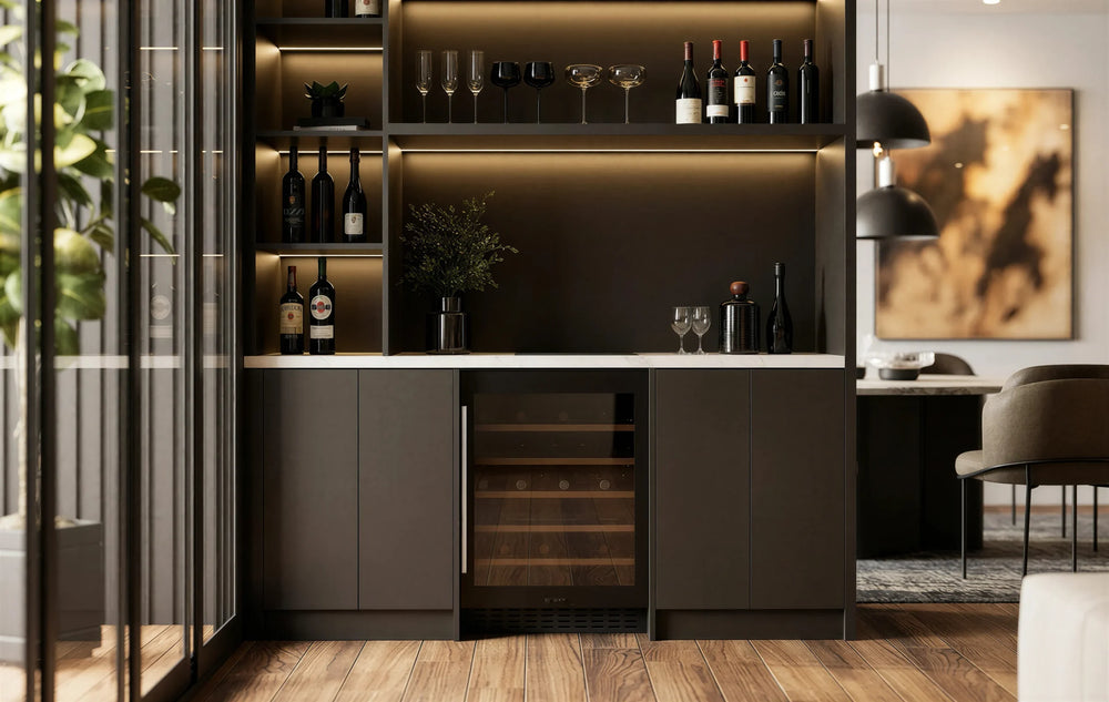 Carlton Bar Unit in London: a charcoal handleless home bar with a white marble worktop, lit shelving, glazed cabinets and a wine cooler; the charcoal bar with its white marble worktop, lit shelving and wine cooler beside the dining table. Made to measure by Metro Home Interiors