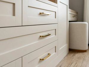 Seraphina fitted bedroom furniture in London: Cashmere Grey shaker wardrobes with brass bar handles; the shaker drawer fronts and brushed brass bar handles up close. Made to measure by Metro Home Interiors