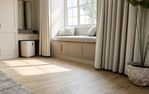 Seraphina fitted bedroom furniture in London: Cashmere Grey shaker wardrobes with brass bar handles; the built-in window seat with a lift-up lid beside the dressing table. Made to measure by Metro Home Interiors
