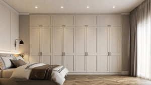 Vivienne fitted bedroom furniture in London: cream shaker wardrobe wall with slim black bar handles; the room from the window end. Made to measure by Metro Home Interiors