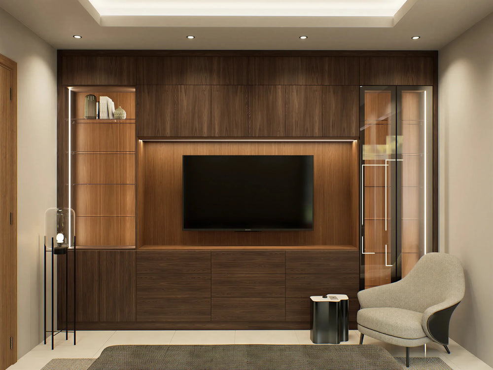 Wigmore media wall in London: a wall-to-wall walnut media wall with the screen on a central panel, glass display columns lit from their edges either side, push-to-open drawers below and a lit pelmet, in a snug with an armchair. Made to measure by Metro Home Interiors