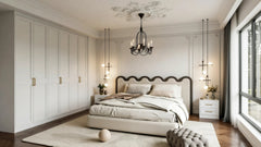 Arabella fitted bedroom furniture in London: ivory in-frame panelled wardrobe wall with brass handles under a chandelier; the ivory panelled wardrobe wall, chandelier and scalloped headboard. Made to measure by Metro Home Interiors