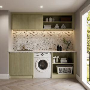 Balham fitted laundry room in London: a sage green fluted run with a brass-tap sink, the washing machine under a terrazzo worktop, open shelving for baskets, a terrazzo splashback and a lit fluted upper cupboard, beside the garden door. Made to measure by Metro Home Interiors