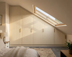 Bespoke slab loft wardrobe in London with fitted doors, sloping ceiling storage and made-to-measure design by Metro home interiors. 