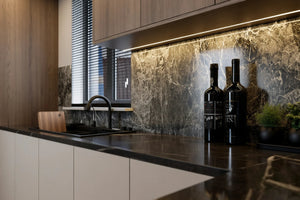 Blackheath Slab Island Kitchen in London: matt white slab base units with oak wall units, a black marble island and splashback, and a black fridge-freezer; the sink run under the window with black marble worktop. Made to measure by Metro Home Interiors