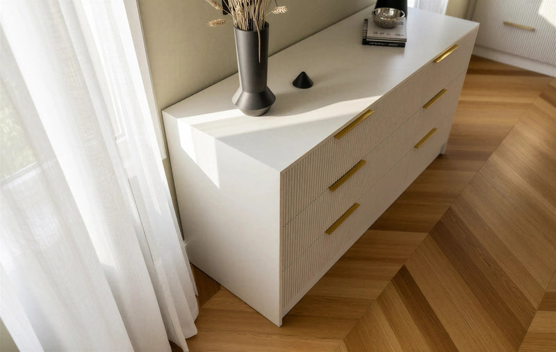 Bloomsbury fluted chest of drawers: the fluted greige fronts and brass bars seen from above on a herringbone floor