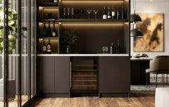 Carlton Bar Unit in London: a charcoal handleless home bar with a white marble worktop, lit shelving, glazed cabinets and a wine cooler; the charcoal bar with its white marble worktop, lit shelving and wine cooler beside the dining table. Made to measure by Metro Home Interiors
