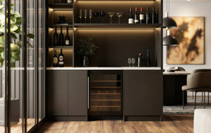 Carlton Bar Unit in London: a charcoal handleless home bar with a white marble worktop, lit shelving, glazed cabinets and a wine cooler; the charcoal bar with its white marble worktop, lit shelving and wine cooler beside the dining table. Made to measure by Metro Home Interiors