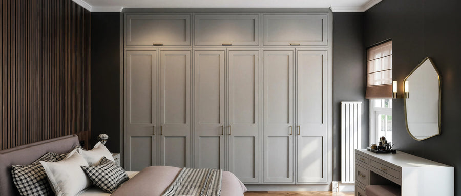 Grey painted MDF shaker fitted wardrobes with a dressing table in a dark-walled bedroom, made to measure in London