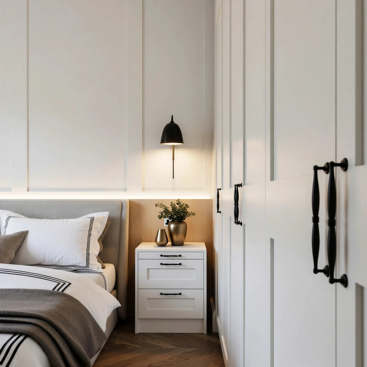Hampstead shaker bedside: a white three-drawer shaker bedside with black handles beside the bed, under a wall light and panelled headboard wall