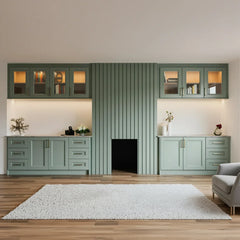 Kew fluted chimney breast panel: a sage green fluted panel over the fireplace between glazed wall cabinets and shaker base cupboards, lit from beneath the cabinets