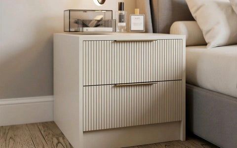 Bedside tables: a cream fluted two-drawer bedside with slim brass bar handles beside an upholstered bed