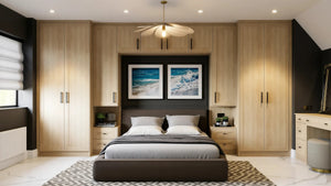 Monroe Oak fitted wardrobes in London: natural sanded solid oak Monroe Oak shaker doors with black bar handles, wrapping the bed with over-bed storage, bedside chests and a dressing table