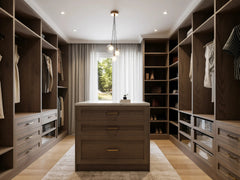 Onslow island walk-in wardrobe in London: a dark oak dressing room with open hanging on both walls, shoe shelving and glazed drawers at the window, and a stone-topped island of shaker drawers in the middle. Made to measure by Metro Home Interiors